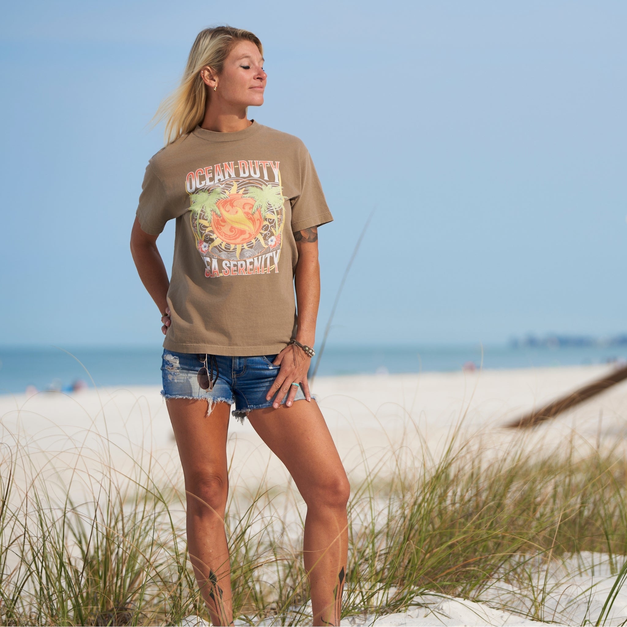 Female wearing a faded brown t-shirt with tropical designs on the beach
