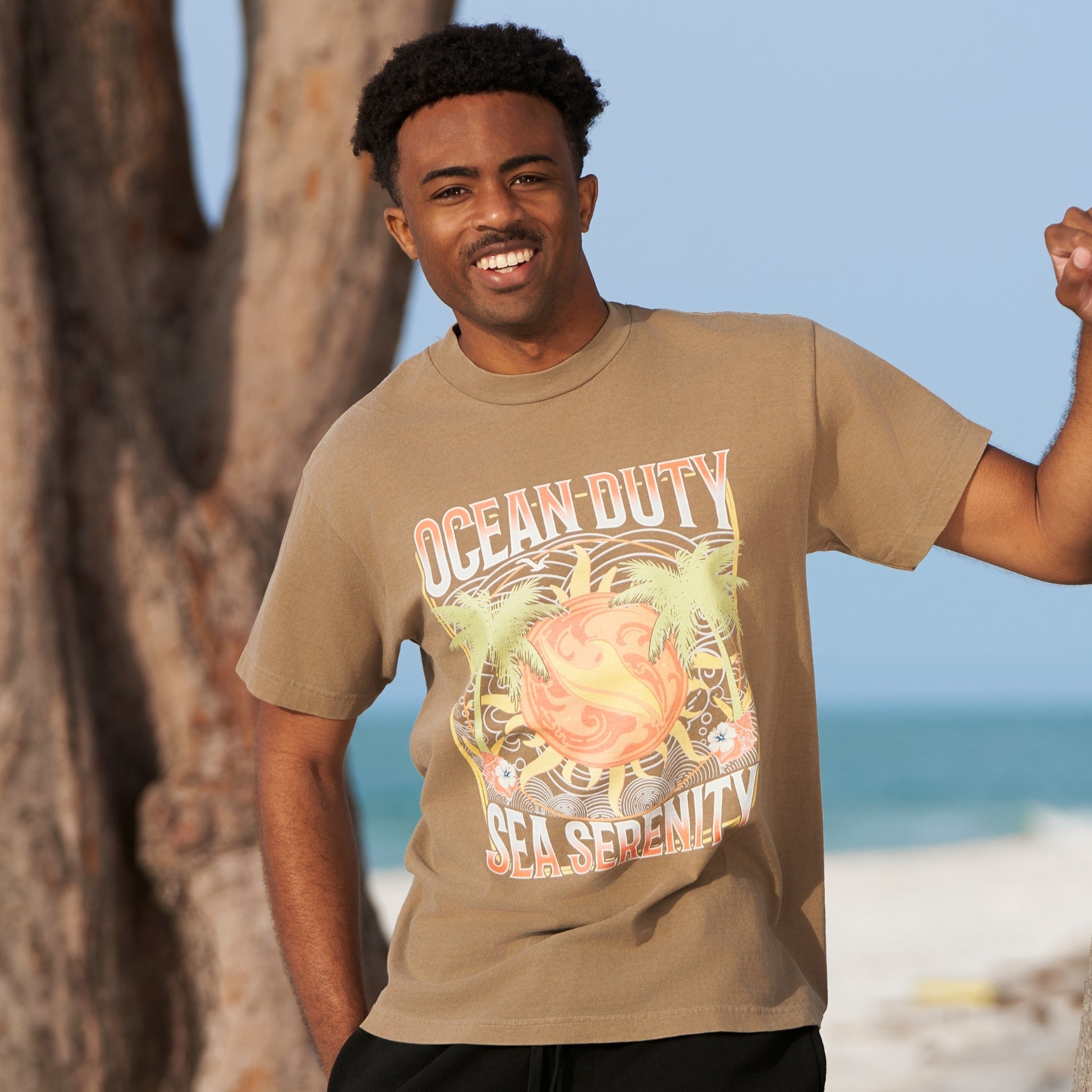 A male wearing a faded brown t-shirt on the beach.