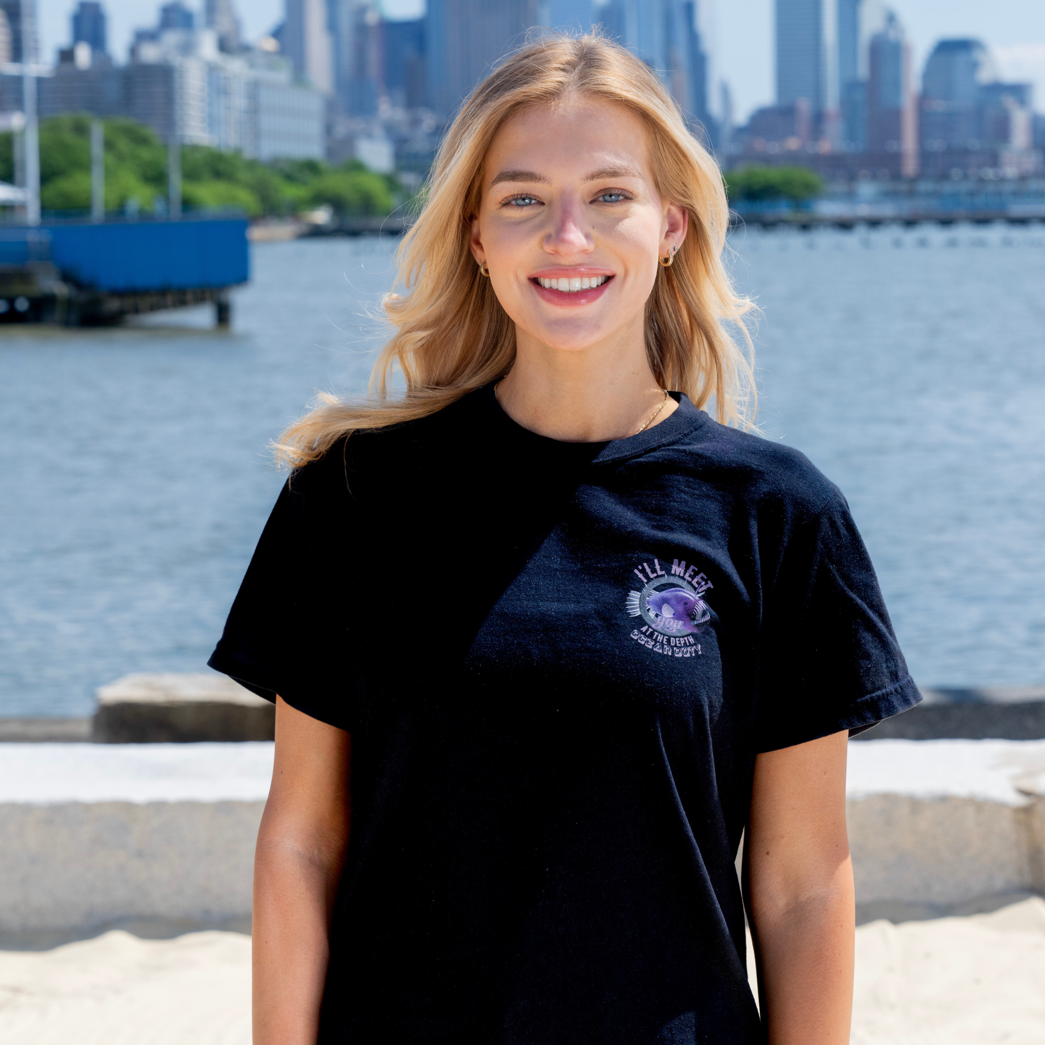 A girl wearing a black t-shirt with a vibrant purple deep sea fish referring to the ocean's depth.