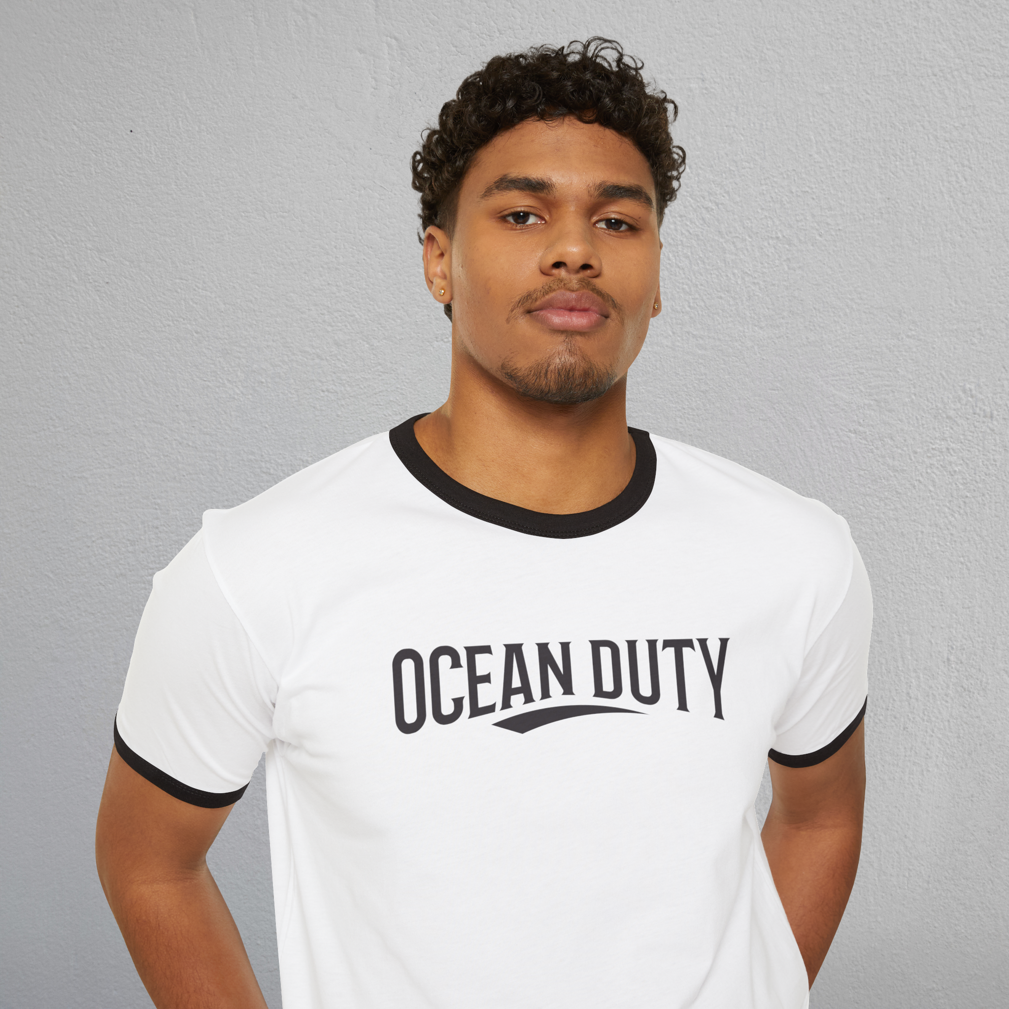 A person wearing a white ringer T-shirt with the words Ocean Duty printed on the front.