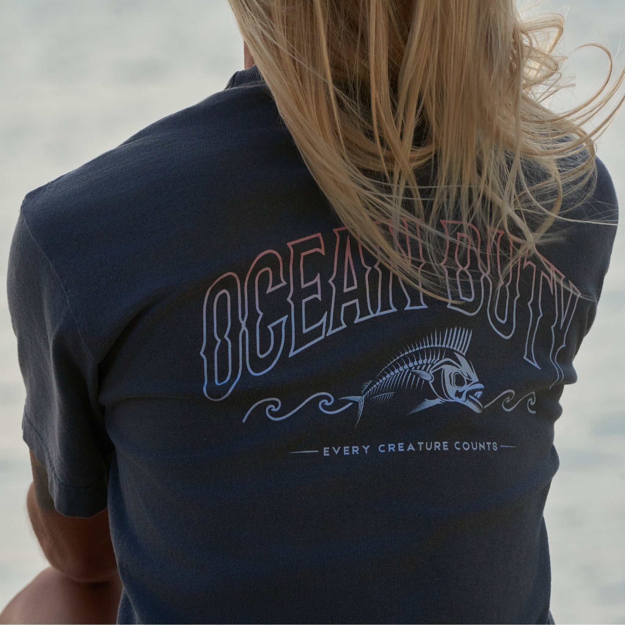 A woman wearing a faded black T-shirt that has an ocean fish graphic.