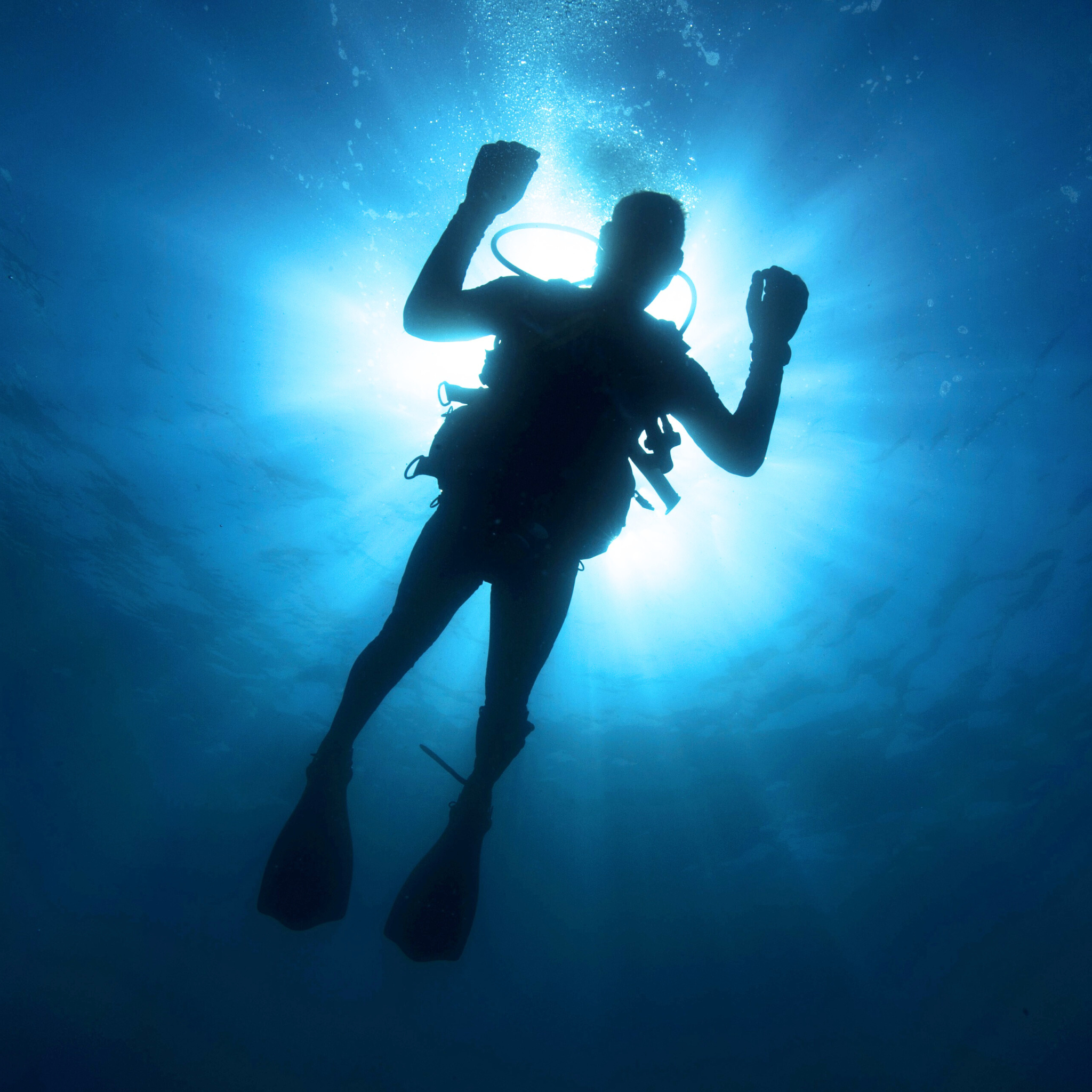 Scuba Diver in Ocean Facing Down With Sun Glaring Behind