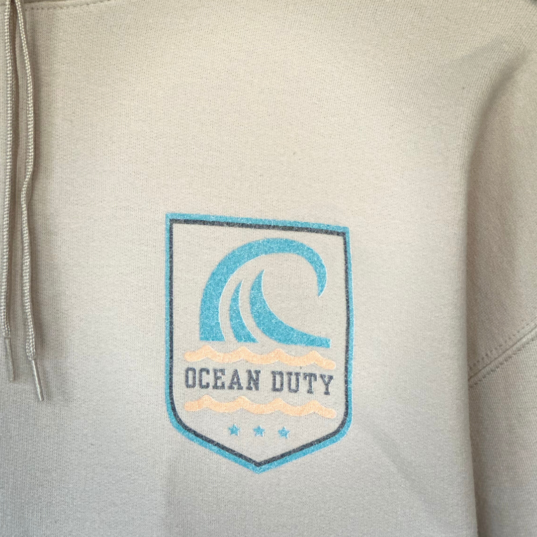 Close up graphic on a sand colored hoodie with large wave graphic on back