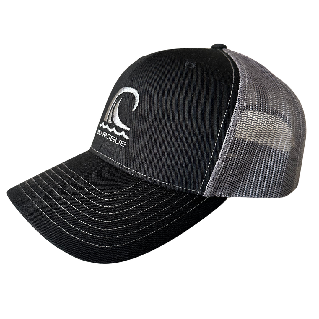 Side view of a black and charcoal grey trucker hat with ocean wave go rogue text embroidery