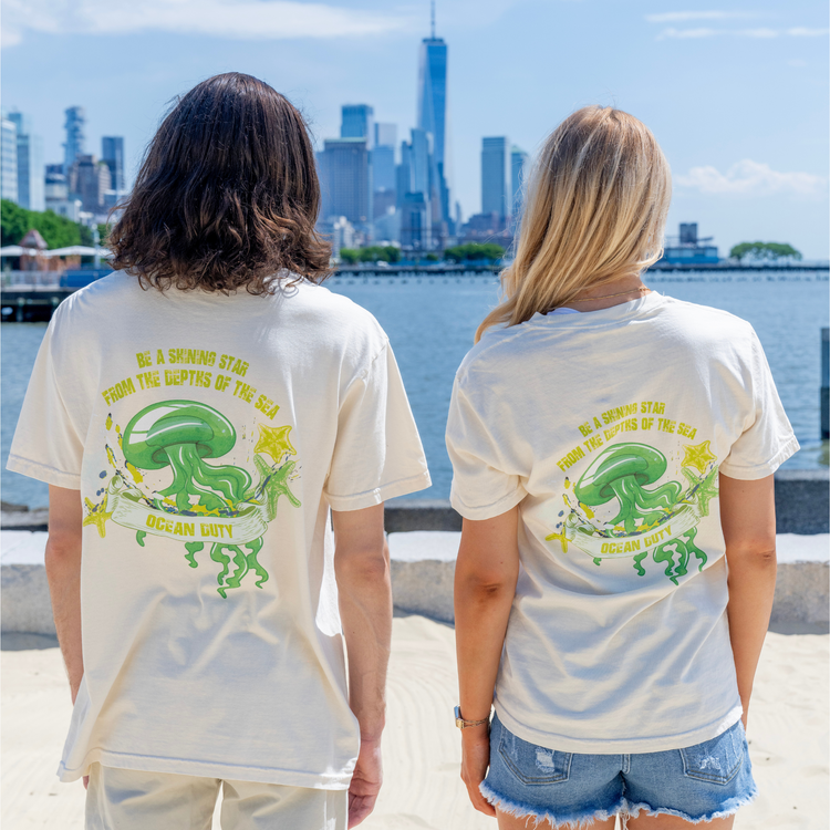 Two people wearing a ivory t-shirt with a bright green jellyfish graphic and print.