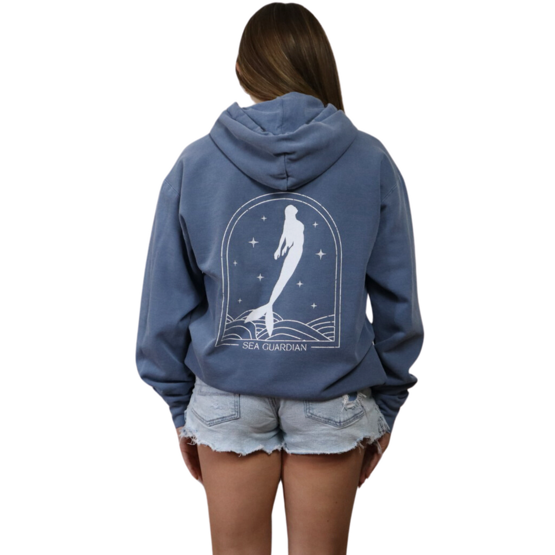 A girl wearing blue hoodie in a blue jean color, featuring a beautifully detailed mermaid graphic on the back, perfect for ocean lovers and casual fashion enthusiasts.