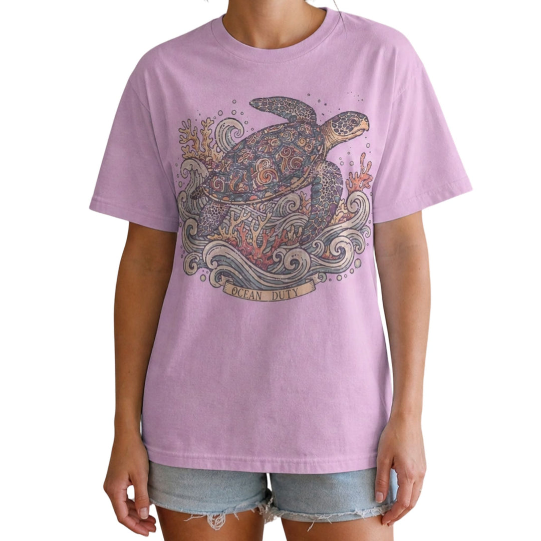 A model wearing a lavender short-sleeve t-shirt with a detailed graphic of a sea turtle, starfish, and waves on the front, paired with denim shorts against a plain white background.